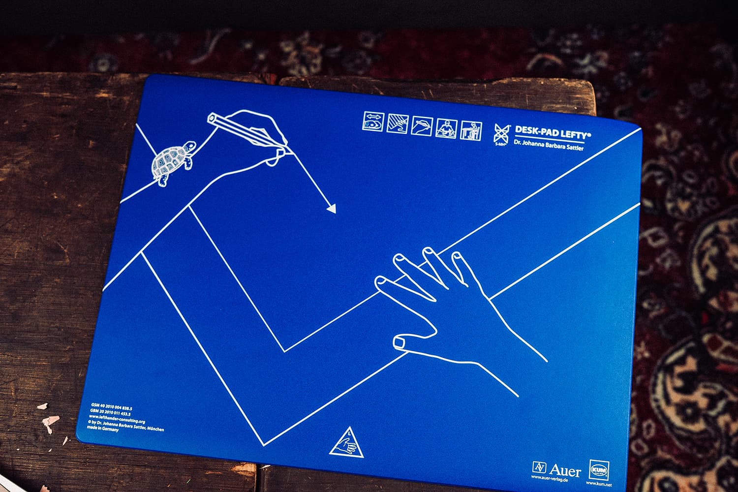 Blaue KUM Desk-Pad Lefty Schreibunterlage mit aufgedruckter Hand- und Blatthaltungs-Zeichnung