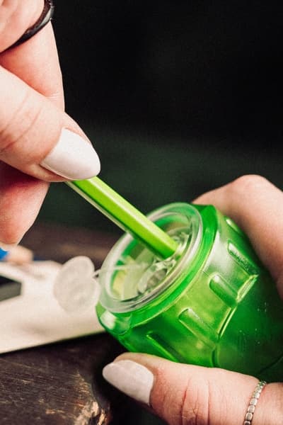 Hand steckt einen grünen Stift in einen grünen KUM Groove Lefty Anspitzer, dunkler Hintergrund