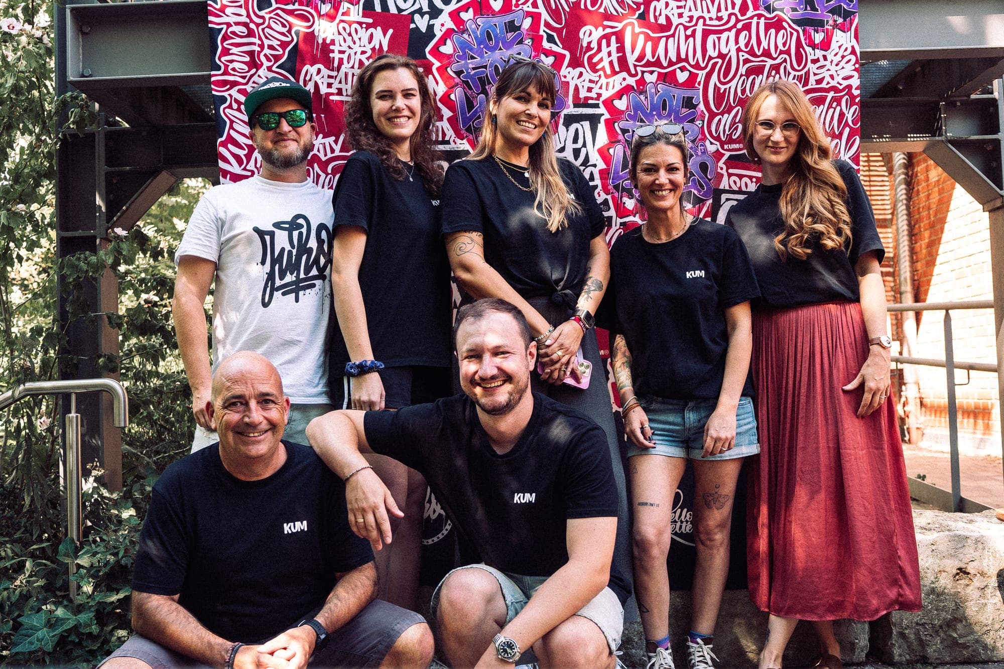 Gruppe in KUM-Shirts vor einer Wand voller Lettering beim #kumtogether-Event 2024