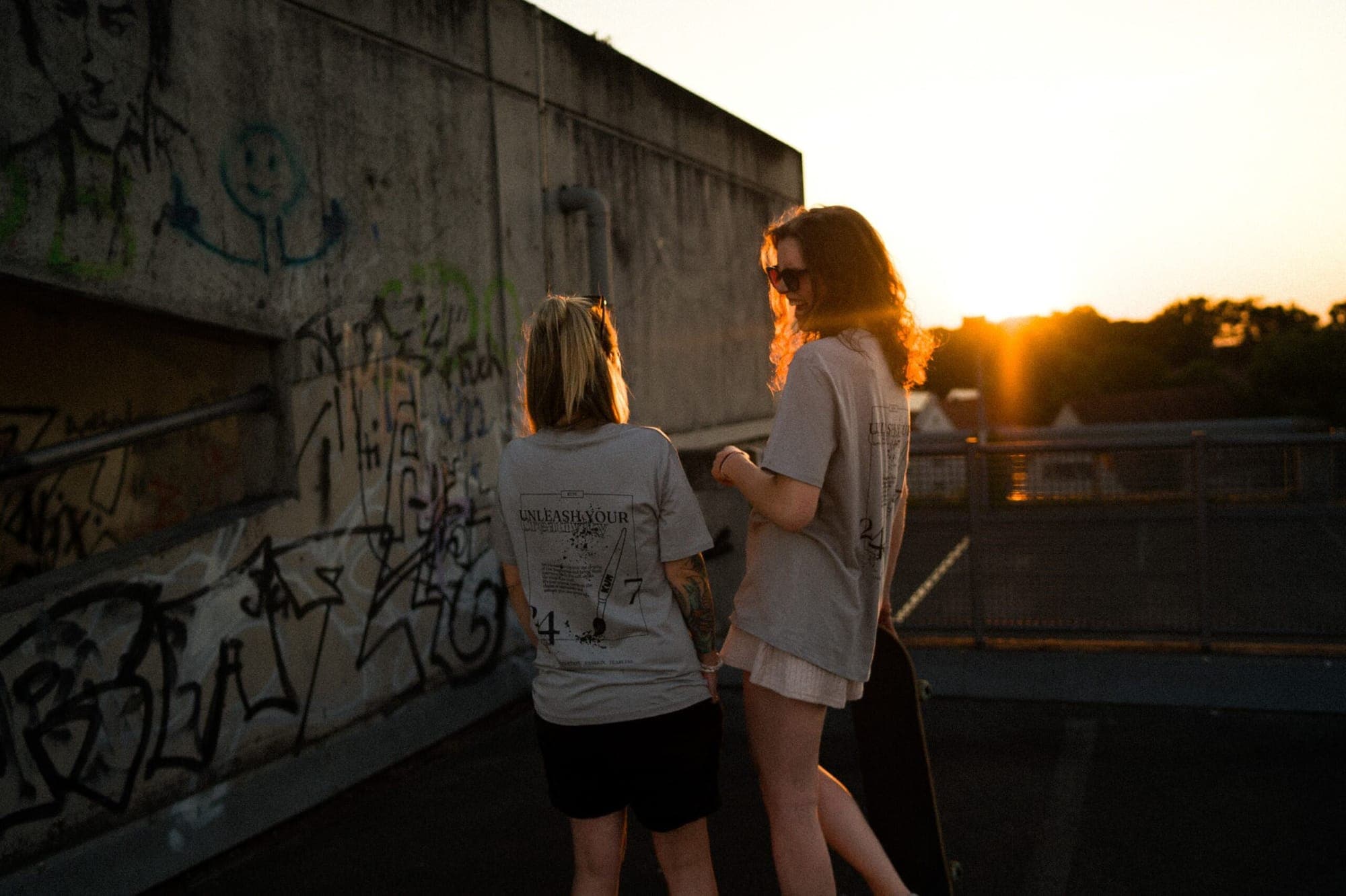 Zwei Frauen in KUM-Shirts auf einem Dach bei Sonnenuntergang