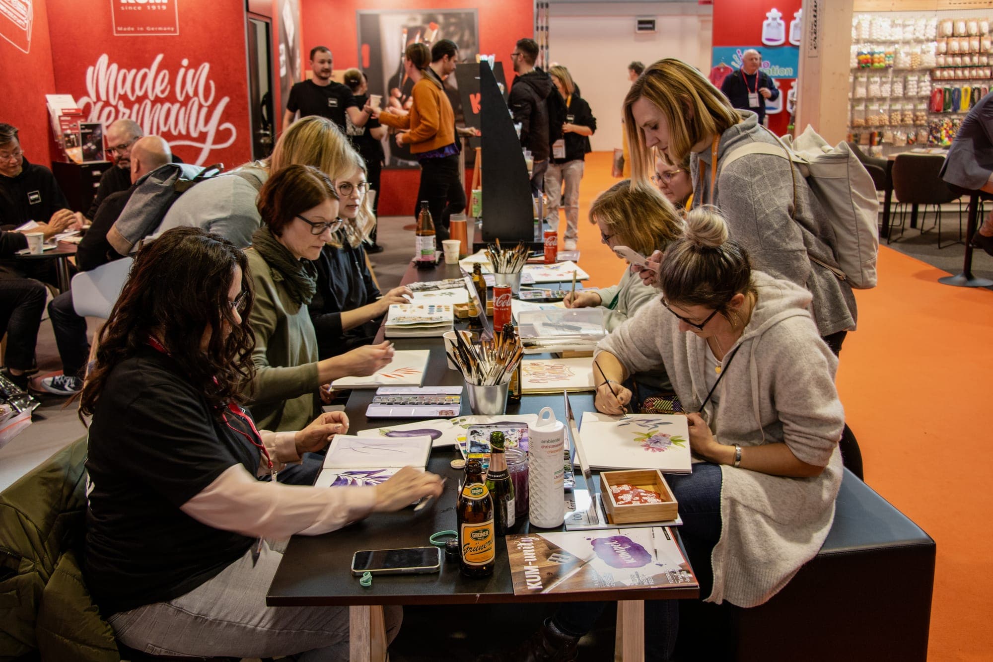 Workshop-Tische am KUM-Stand, im Hintergrund die rote Wand mit Passion for Creativity